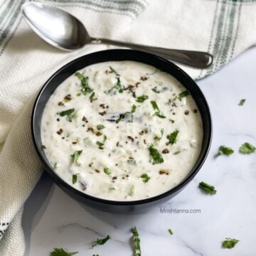 A black color bowl is with vegan raita.