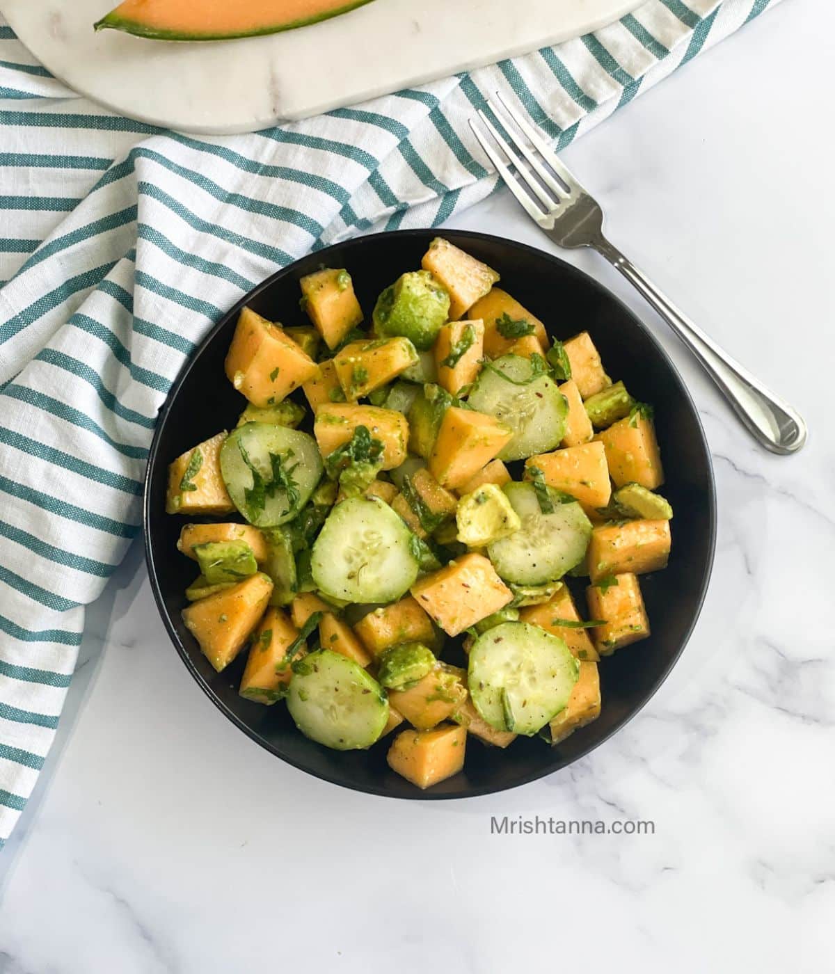 a black plate is with cantaloupe salad.