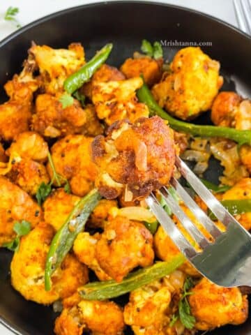 A fork is holding one of the cauliflower 65 bites.