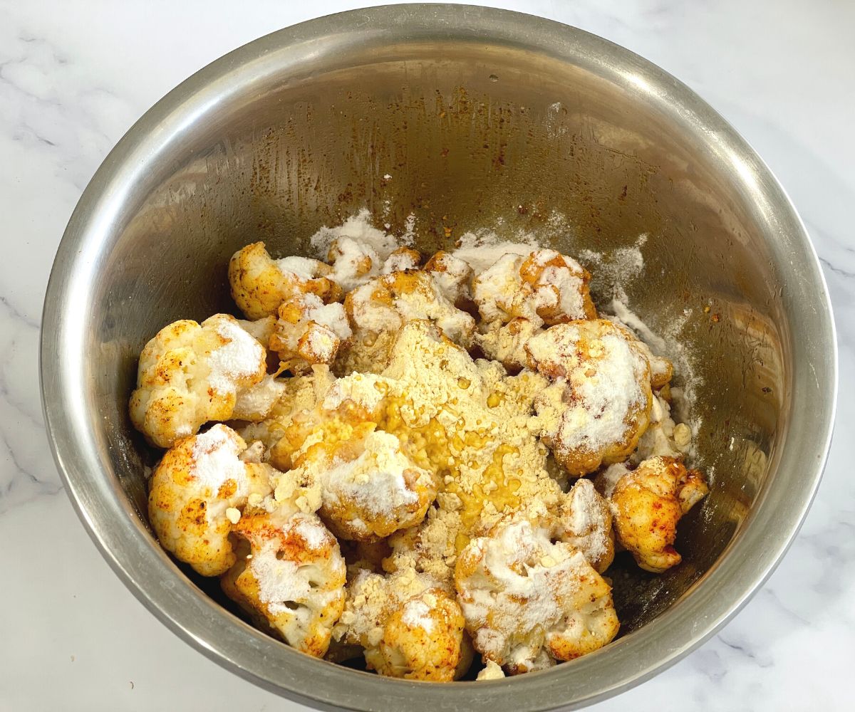A bowl is with cauliflower florets and flour.
