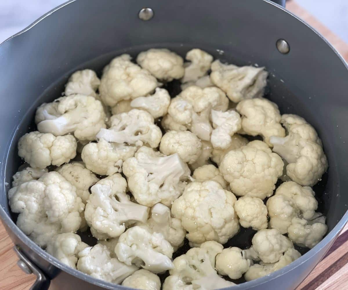 A pot is with hot water and cauliflower florets.