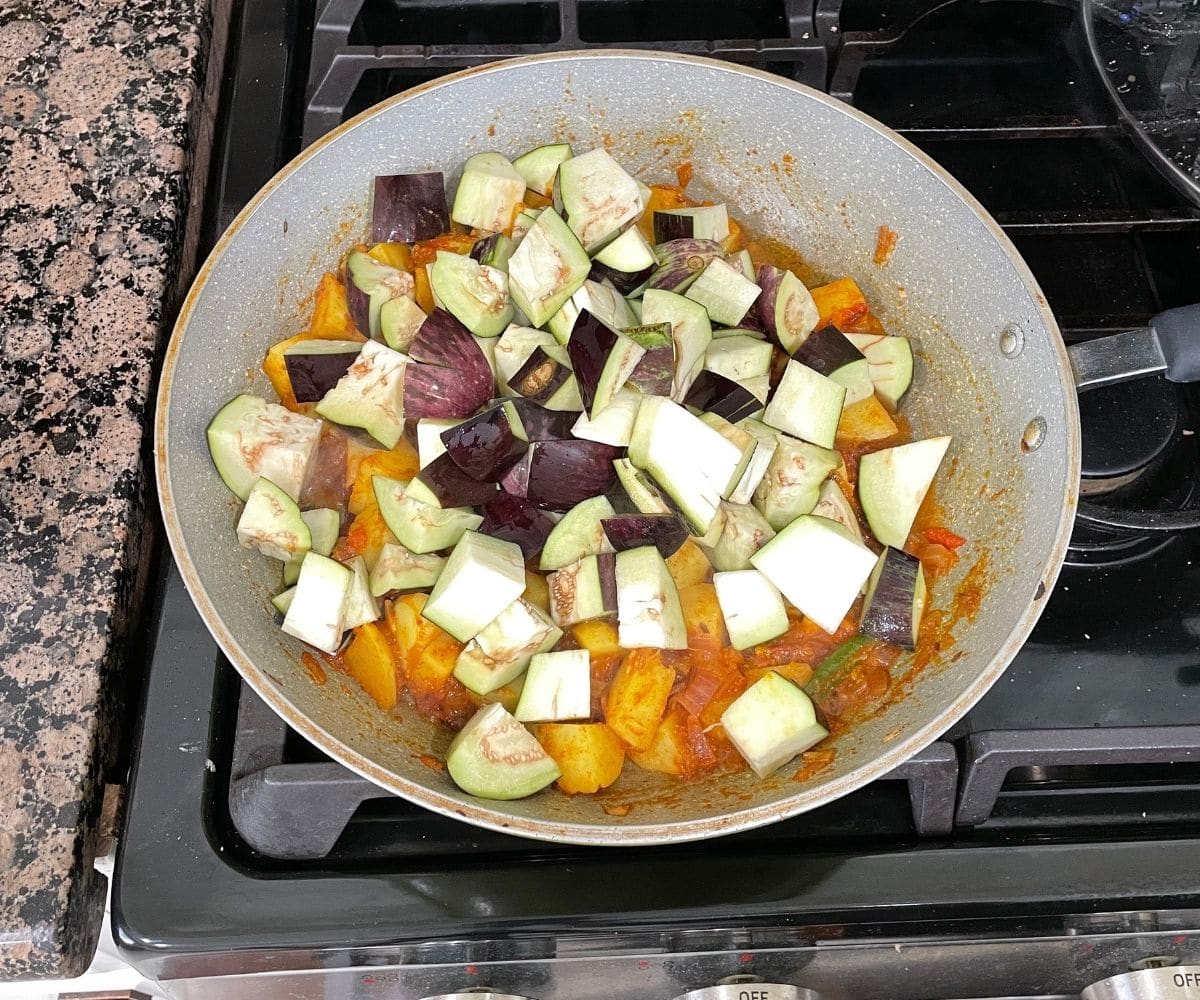 A pan is with aloo baingan sabji over the heat.