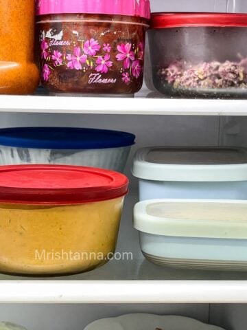 Containers filled with curries and placed inside the fridge.