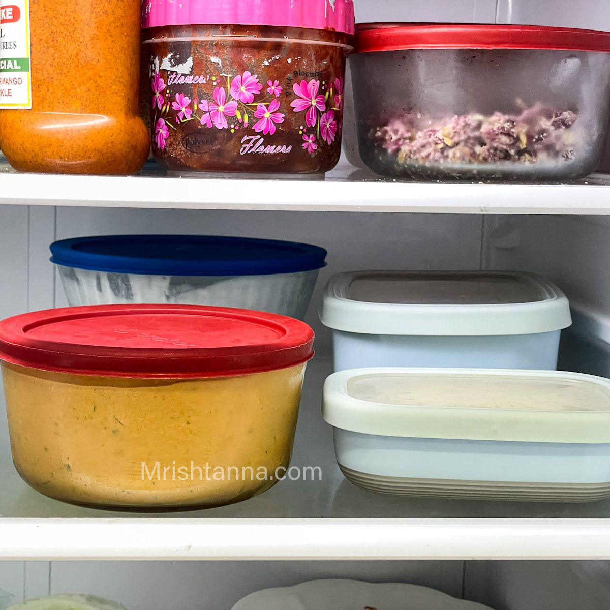 Containers filled with curries and placed inside the fridge.