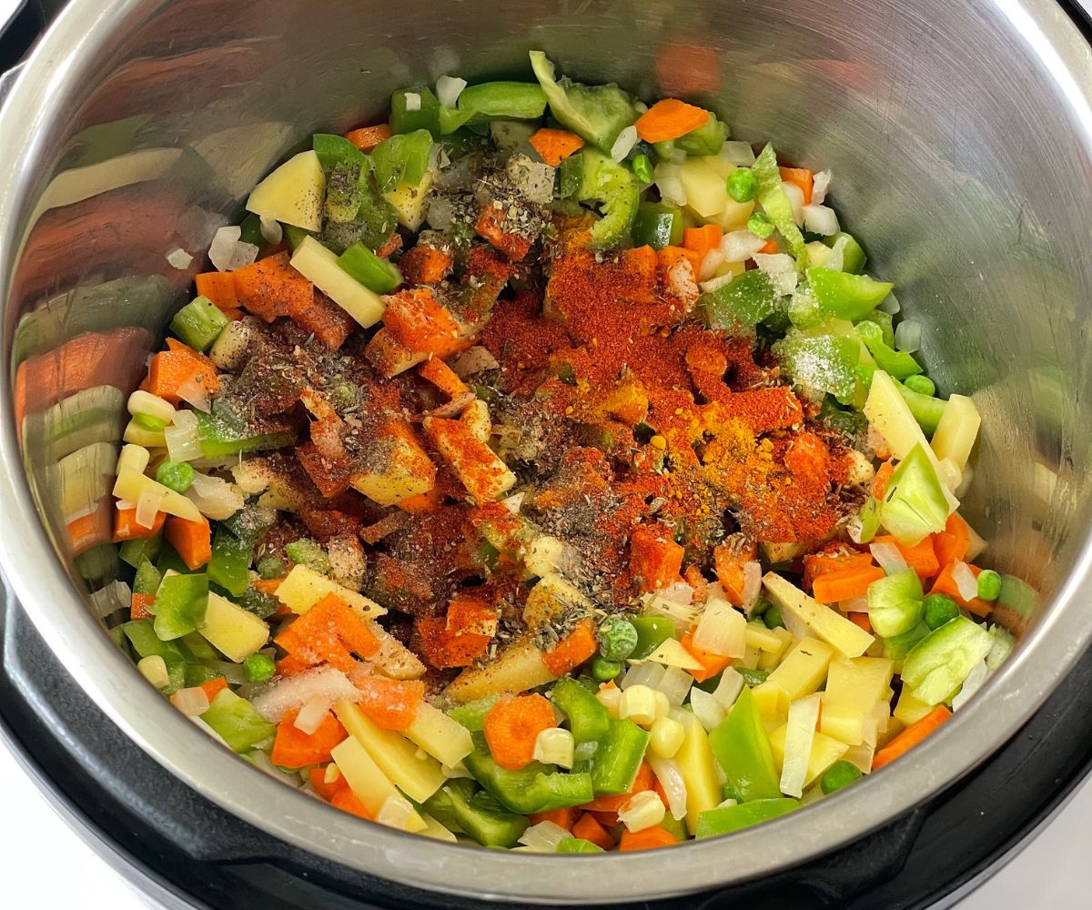 A pot is with vegetables and spices on cooking mode.