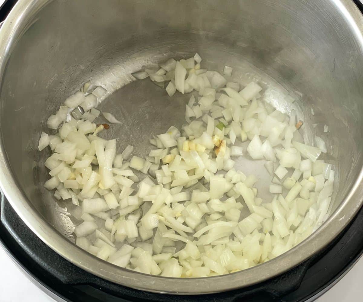 An instant pot is with oil, onions on saute mode.