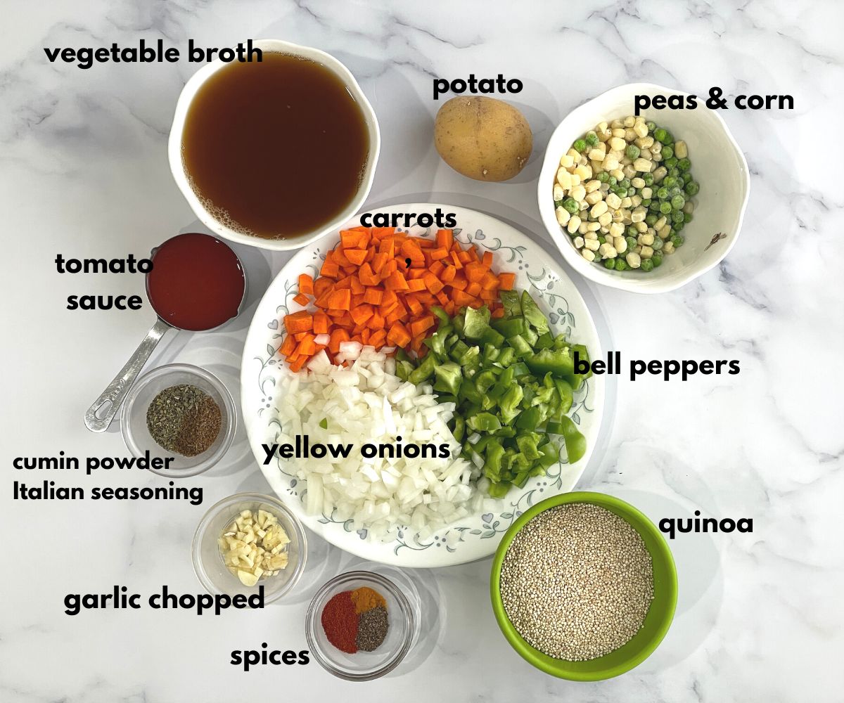 A table is filled with plates and bowl of quinoa vegetable soup ingredients.