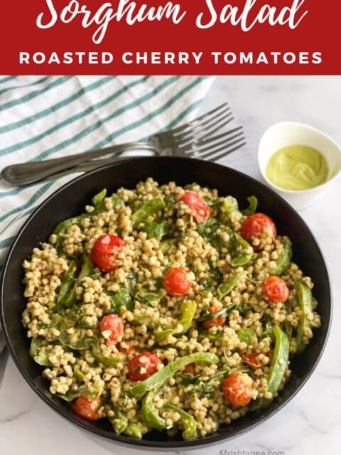 A plate of sorghum salad with cherry tomatoes is on the cloth napkins.