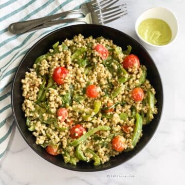 Head shot of plate with sorghum salad and fork on the side and avocado dressing.