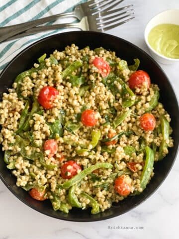 Head shot of plate with sorghum salad and fork on the side and avocado dressing.