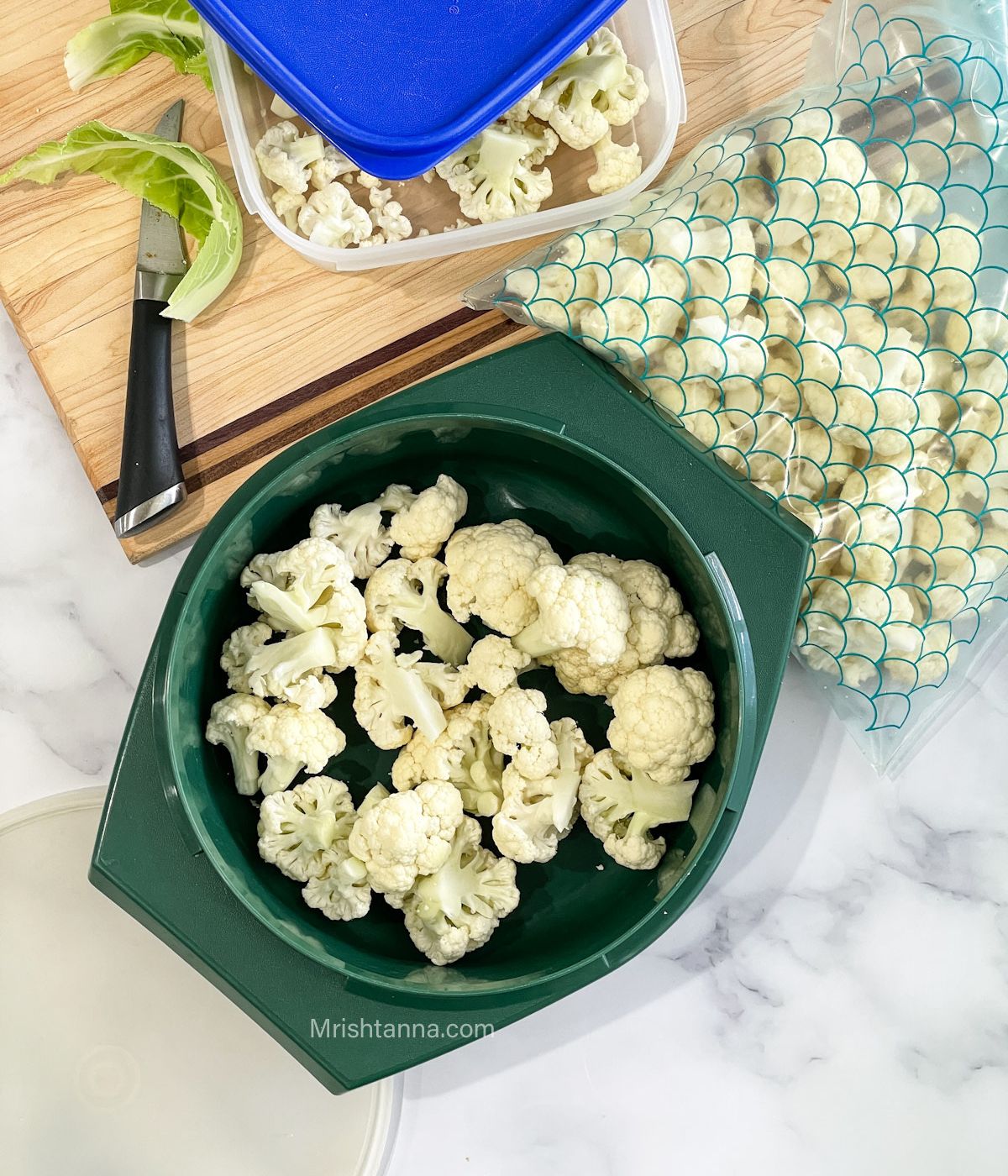 A Tupperware box and zip lock bags are with cauliflower florets on the table.