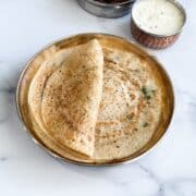 A plate of mixed lentil dosa and a bowl of chutney is on the table.