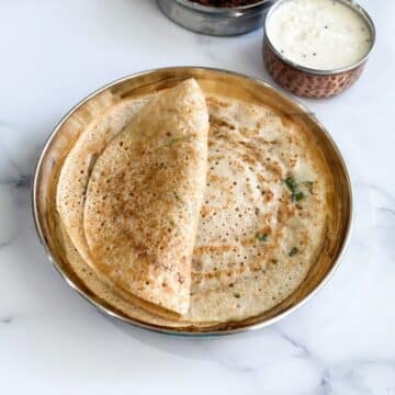 A plate of mixed lentil dosa and a bowl of chutney is on the table.