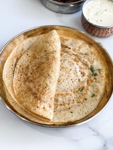 A plate of mixed lentil dosa and a bowl of chutney is on the table.