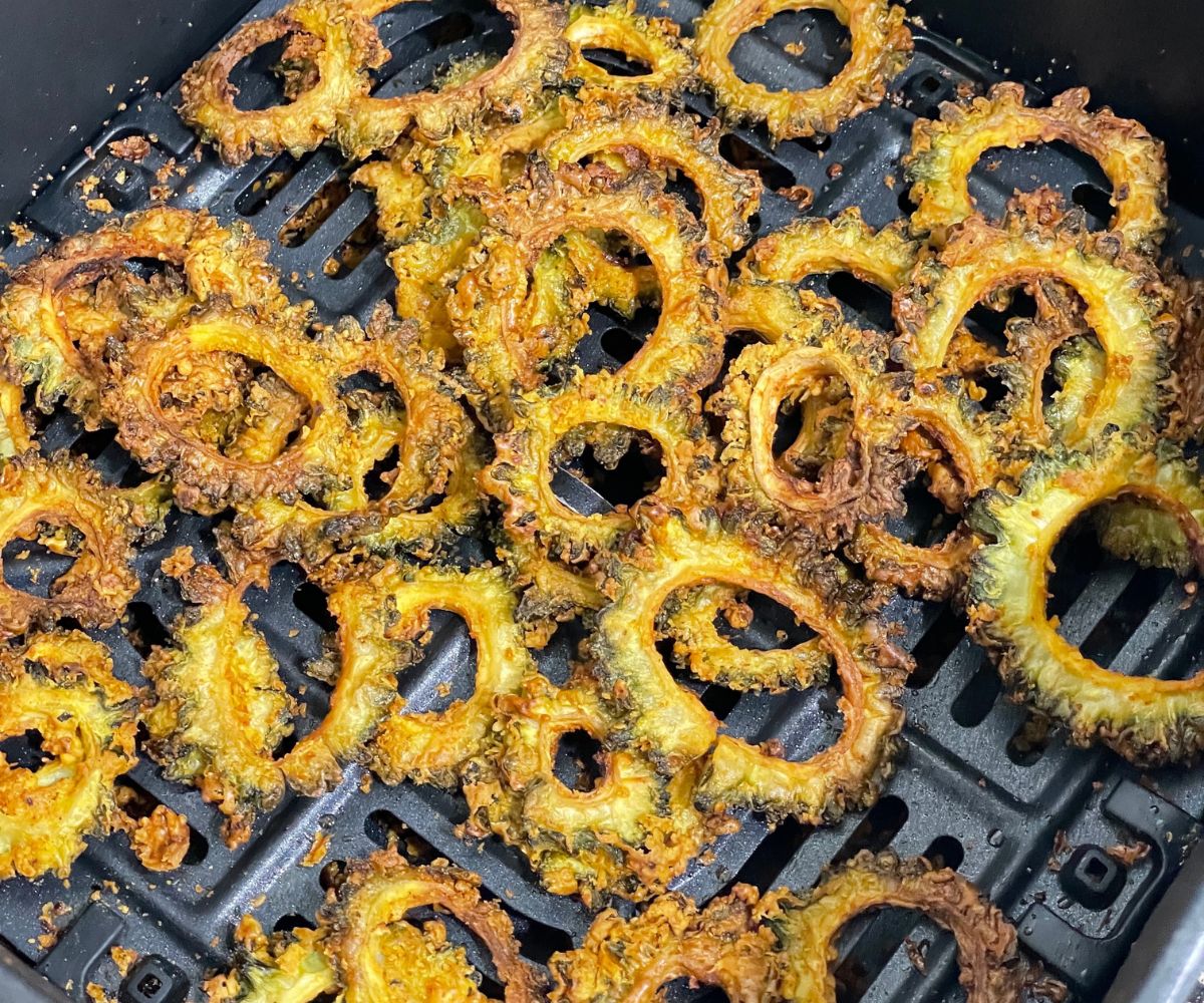 Air fryer basket is with fried karela chips.