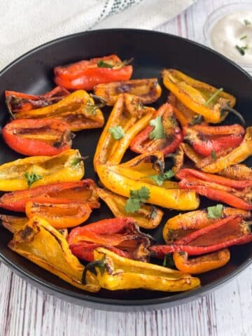 A plate of air fryer roasted mini peppers are on the table.