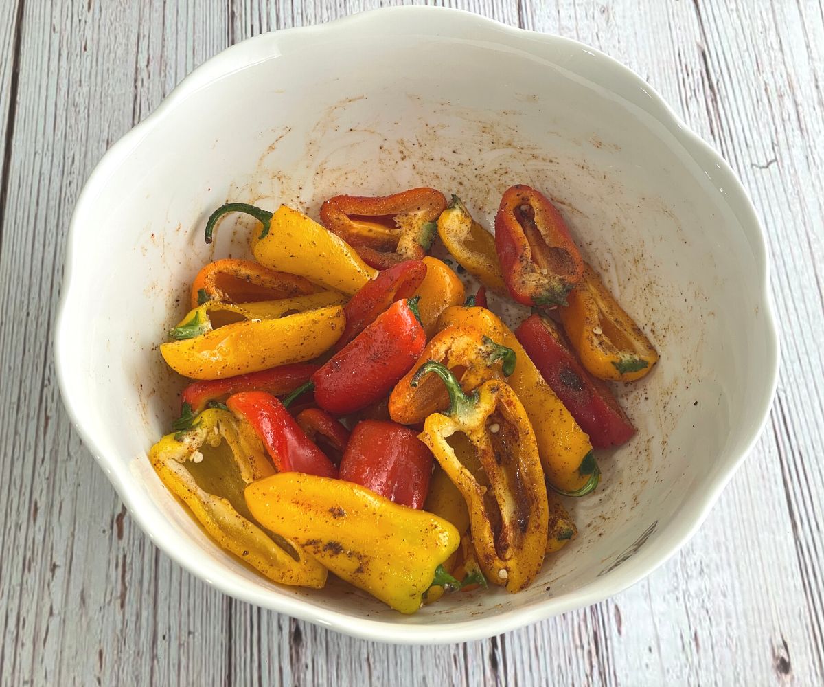 A bowl is with spices coated mini peppers.