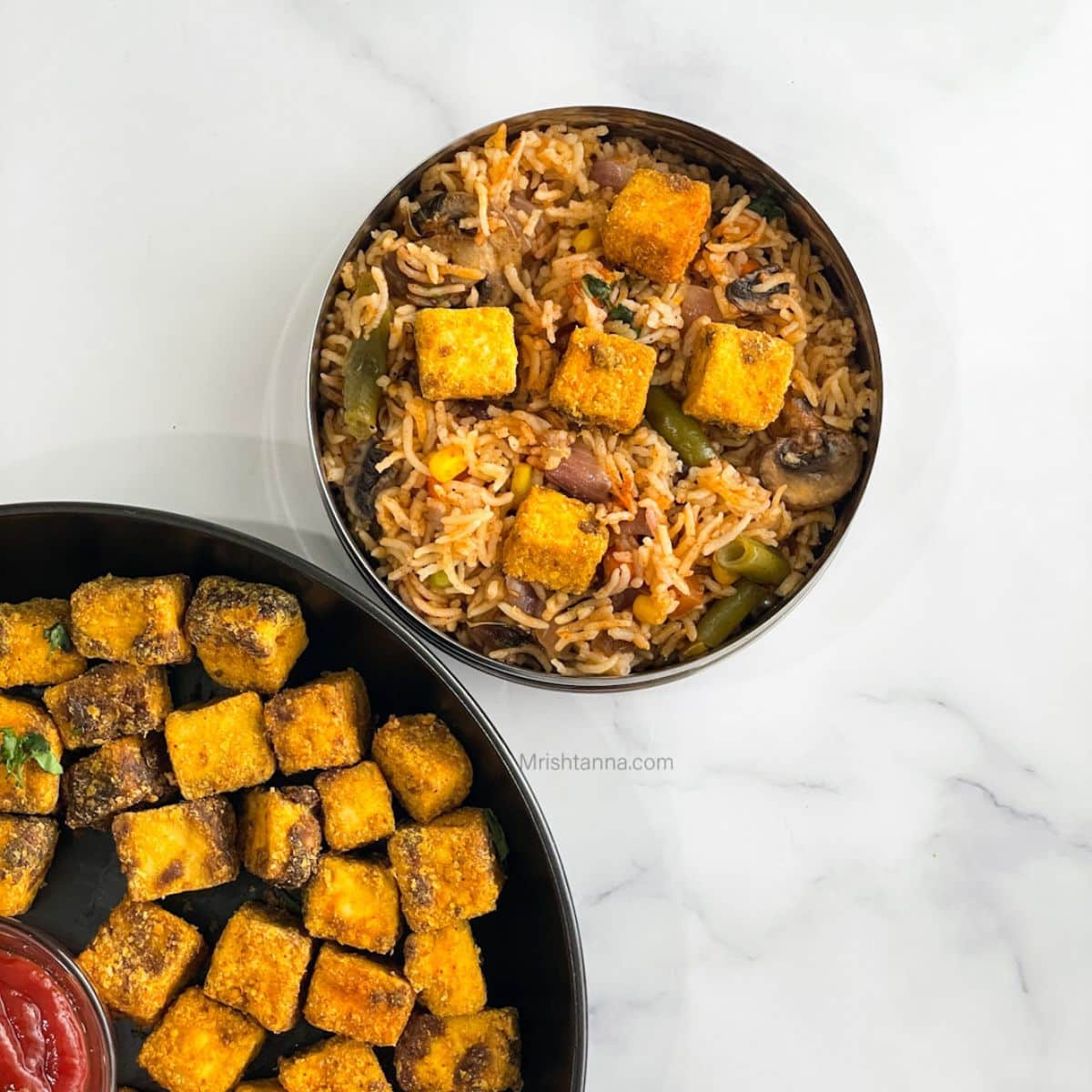 A box with vegetable rice and topped with air fryer tofu nuggets.