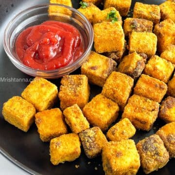 Close up of a fried tofu nuggets and a bowl of tomato ketchup.