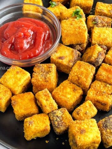 Close up of a fried tofu nuggets and a bowl of tomato ketchup.
