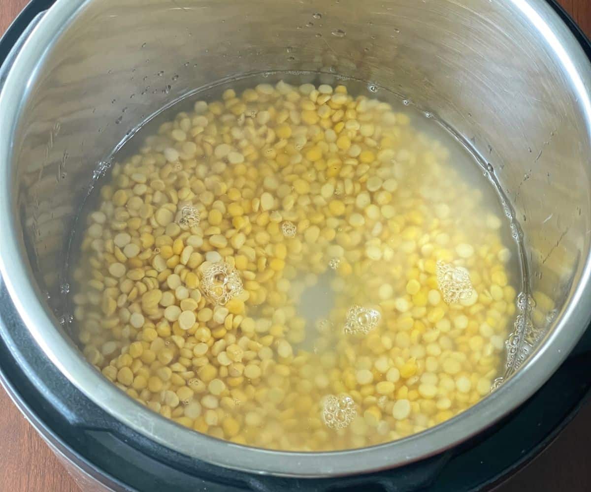 An instant pot is with soaked chana dal and water.