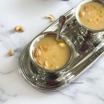 A bowl of chana dal payasam is on the table with a spoon inserted.