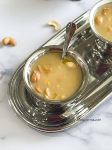 A bowl of chana dal payasam is on the table with a spoon inserted.