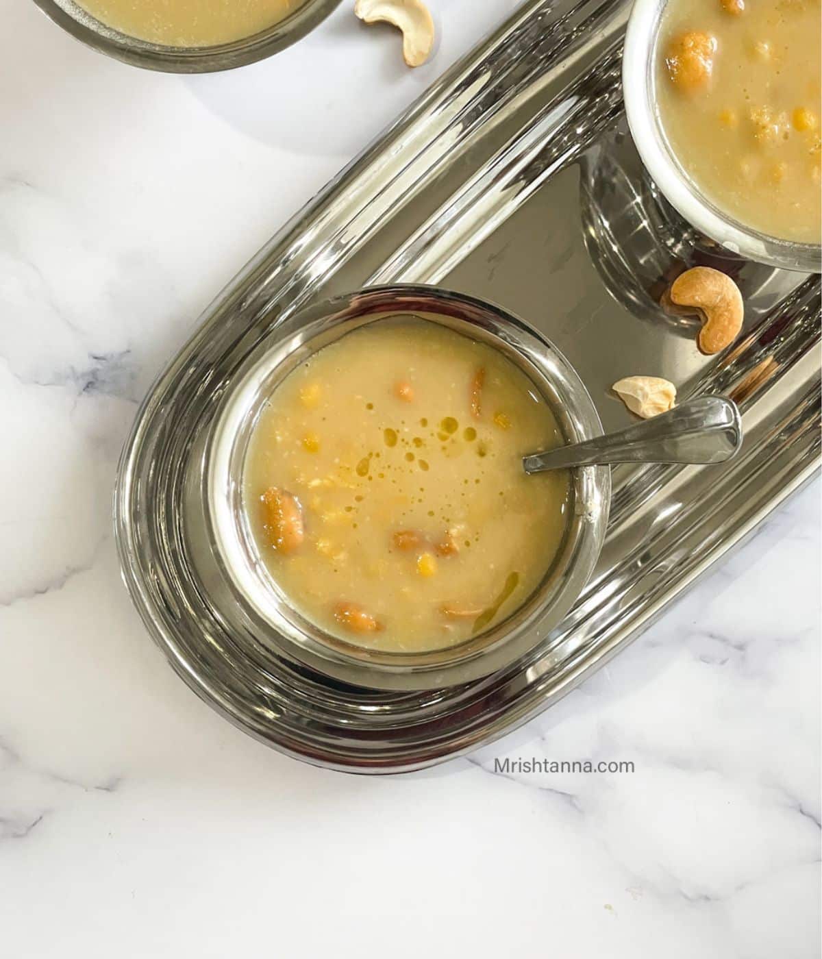 Head shot of steel bowl with chana dal payasam and spoon inserted.