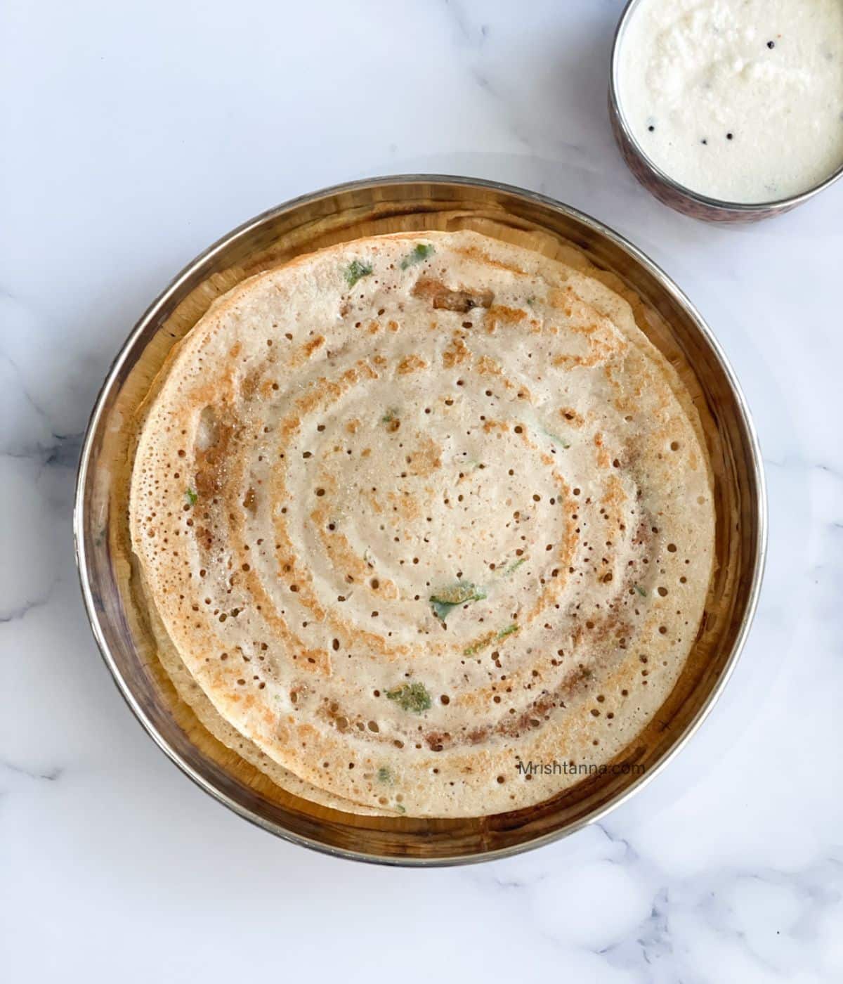 Head shot of adai dosa which is placed on the plate with a bowl of coconut chutney.