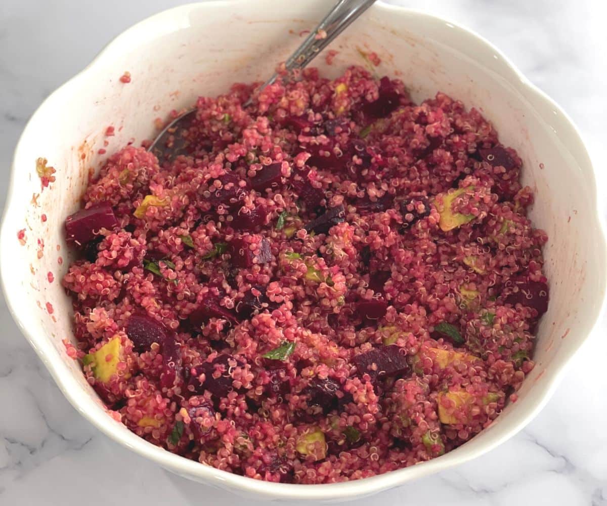 A large bowl is with quinoa and beet salad on the table.