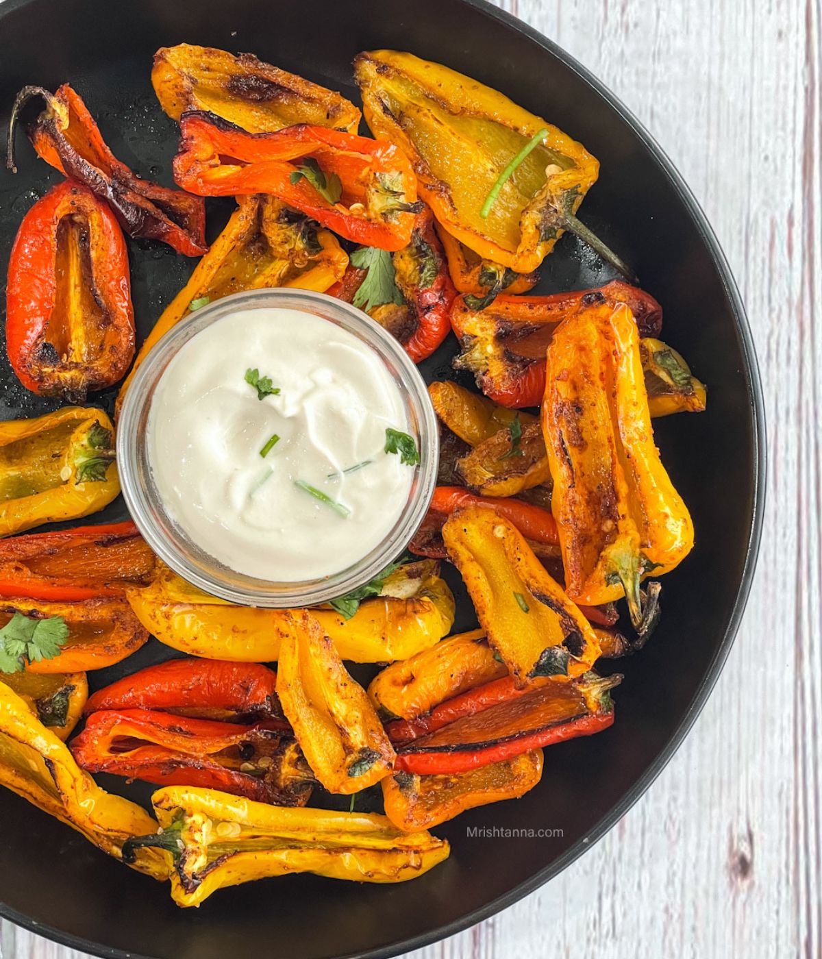 Close up of roasted mini peppers and vegan dip on the plate.