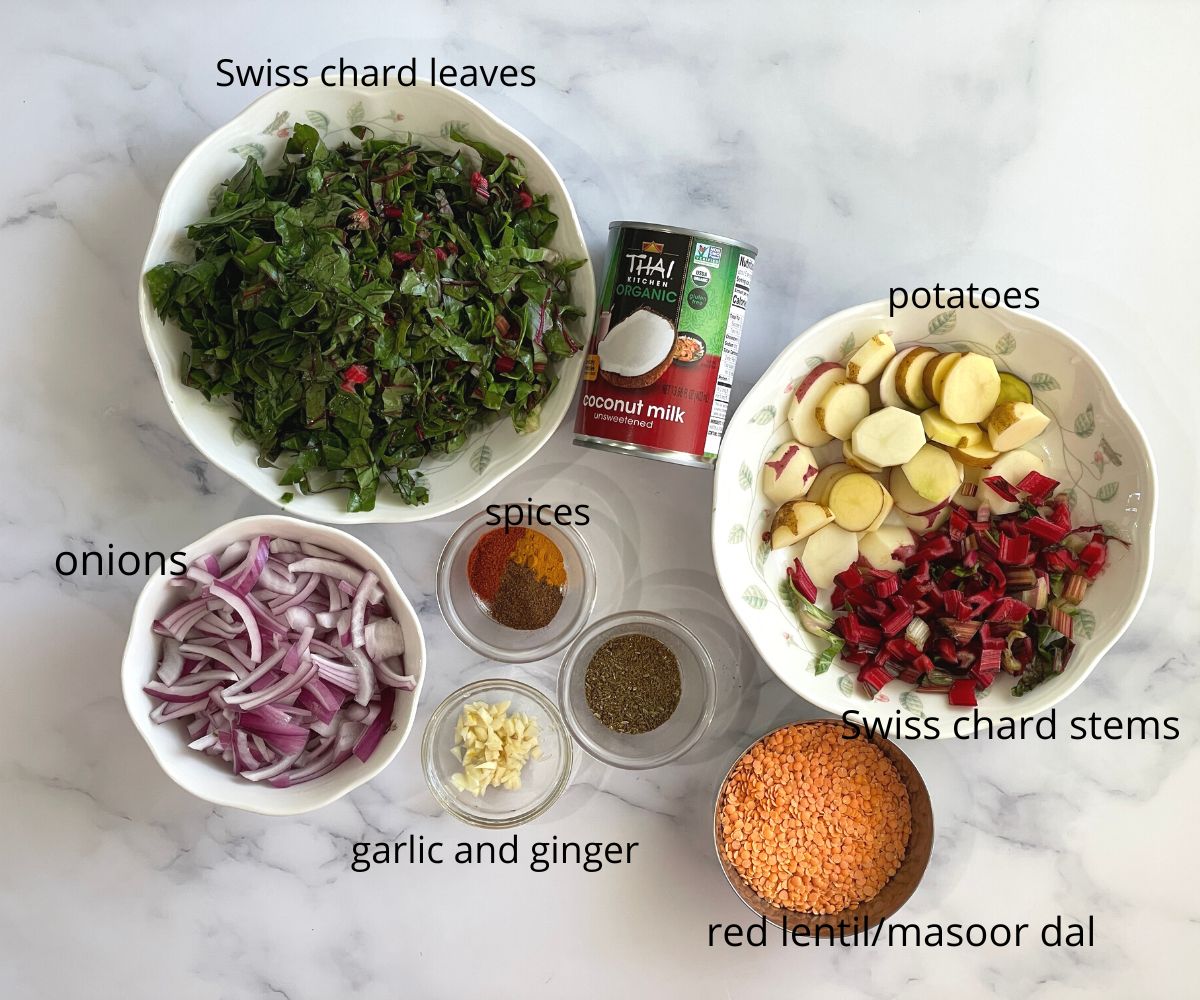 A surface is filled with swiss chard curry ingredients.