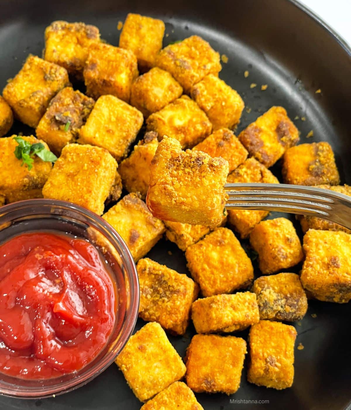 Close up of a fork holding  tofu nuggets.