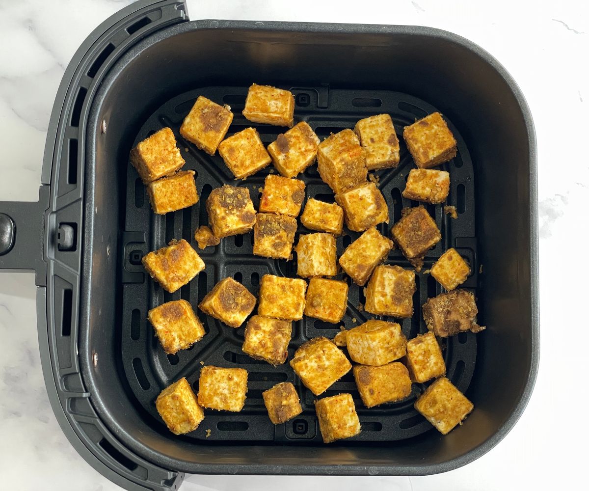 Air fryer basket is with tofu nuggets.