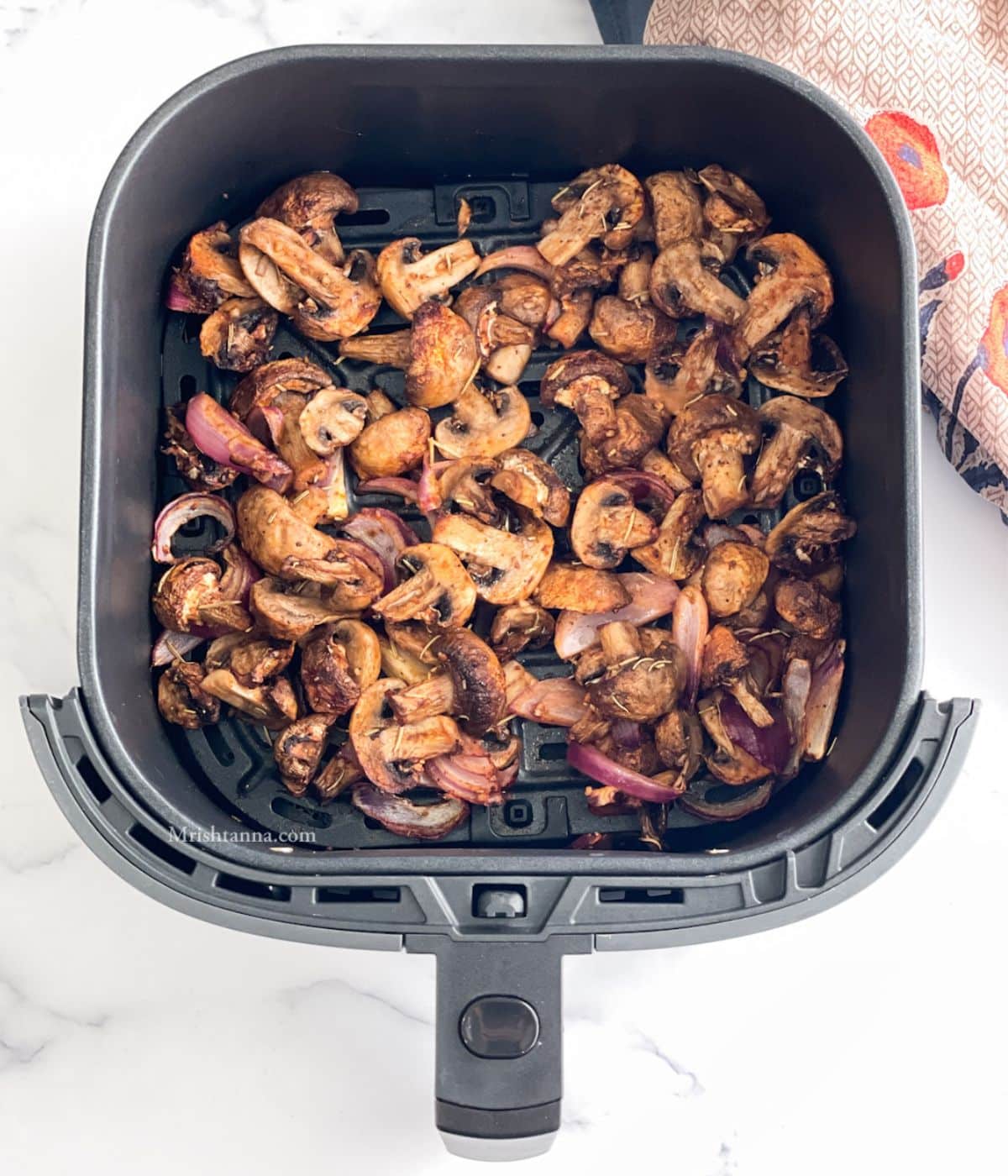 Air fryer basket is with roasted mushrooms and onions.