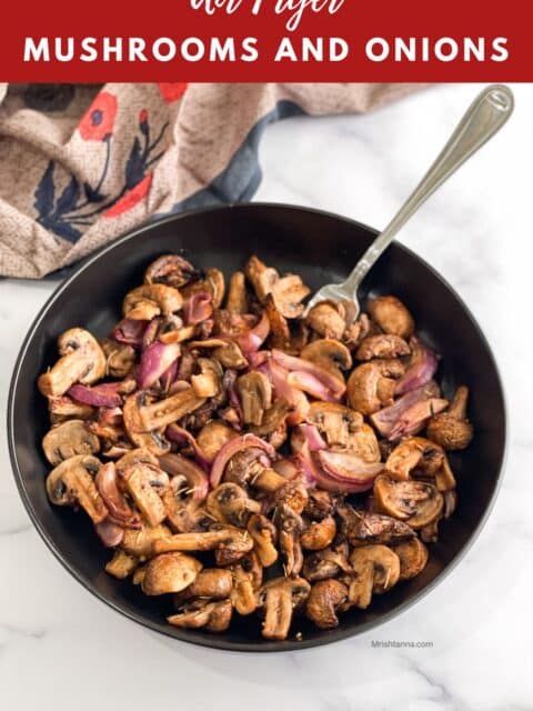 A plate of air fried mushrooms and onions is on the table with a fork inserted.