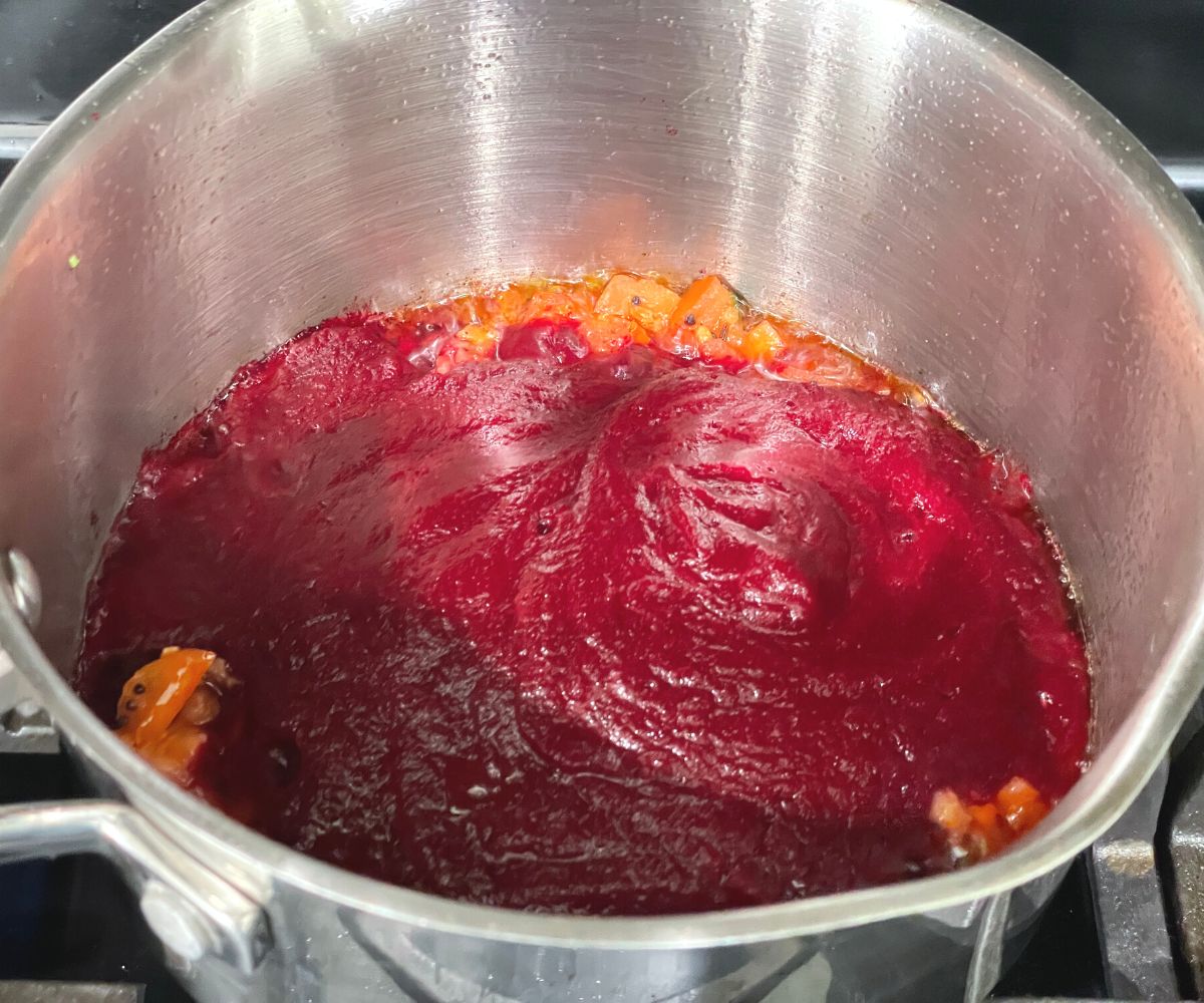 A pot is with spice mixture and beetroot puree over the heat.