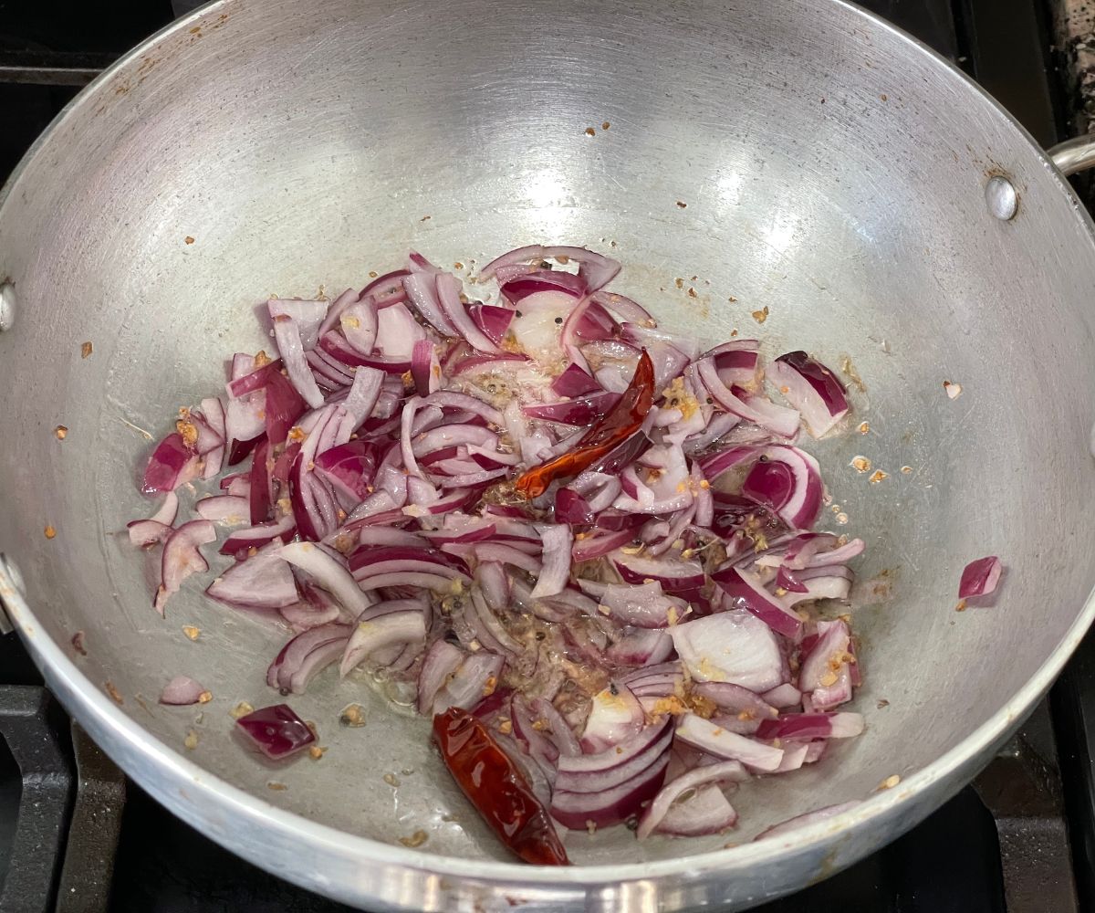 A pot is with oil, spices and chopped onions over the heat.