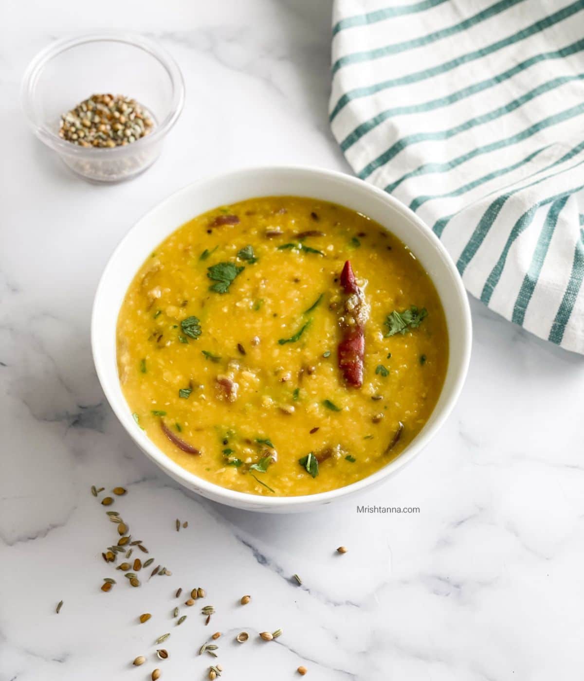 A wite bowl is with Bengali masoor dal.