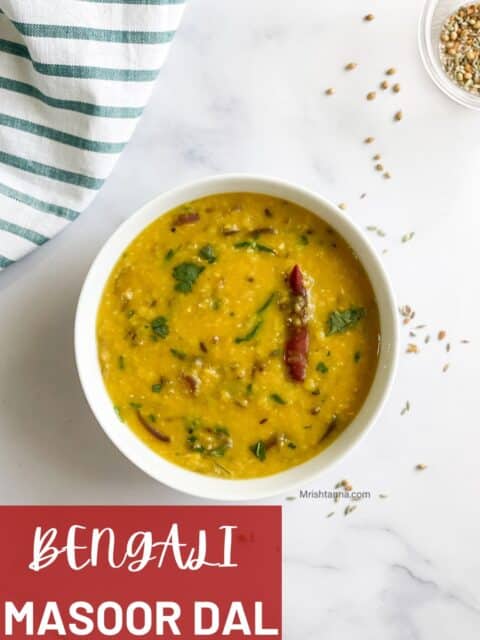 A bowl of red lentil dal is on the table.