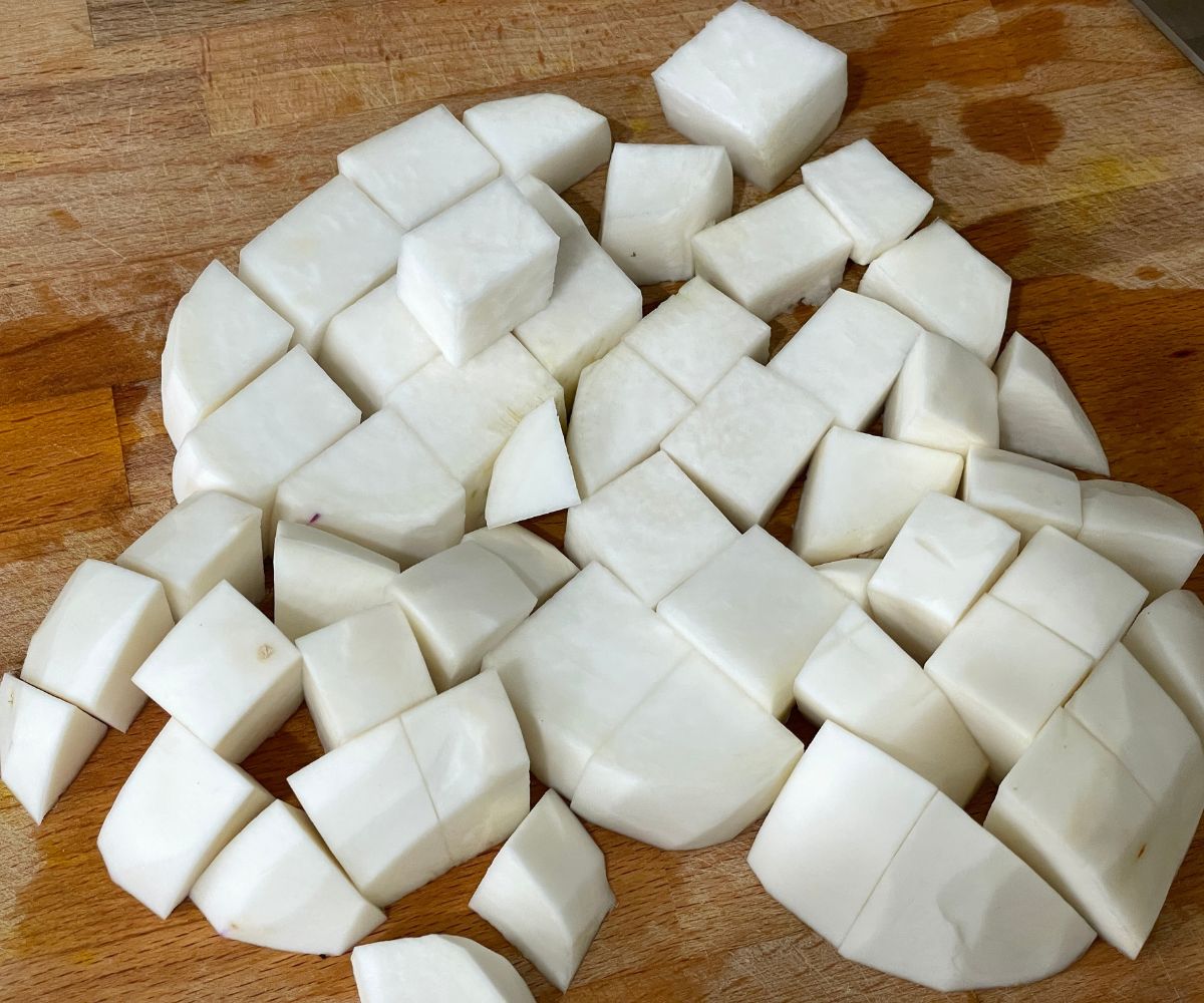 Wooden board is with cubed turnips.