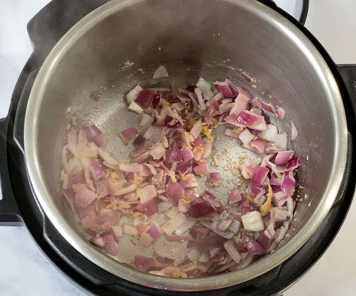 An instant pot is with butter, onions, and ginger garlic on the saute mode.