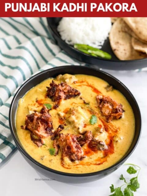 A bowl of Punjabi Kadhi pakora is on the table.