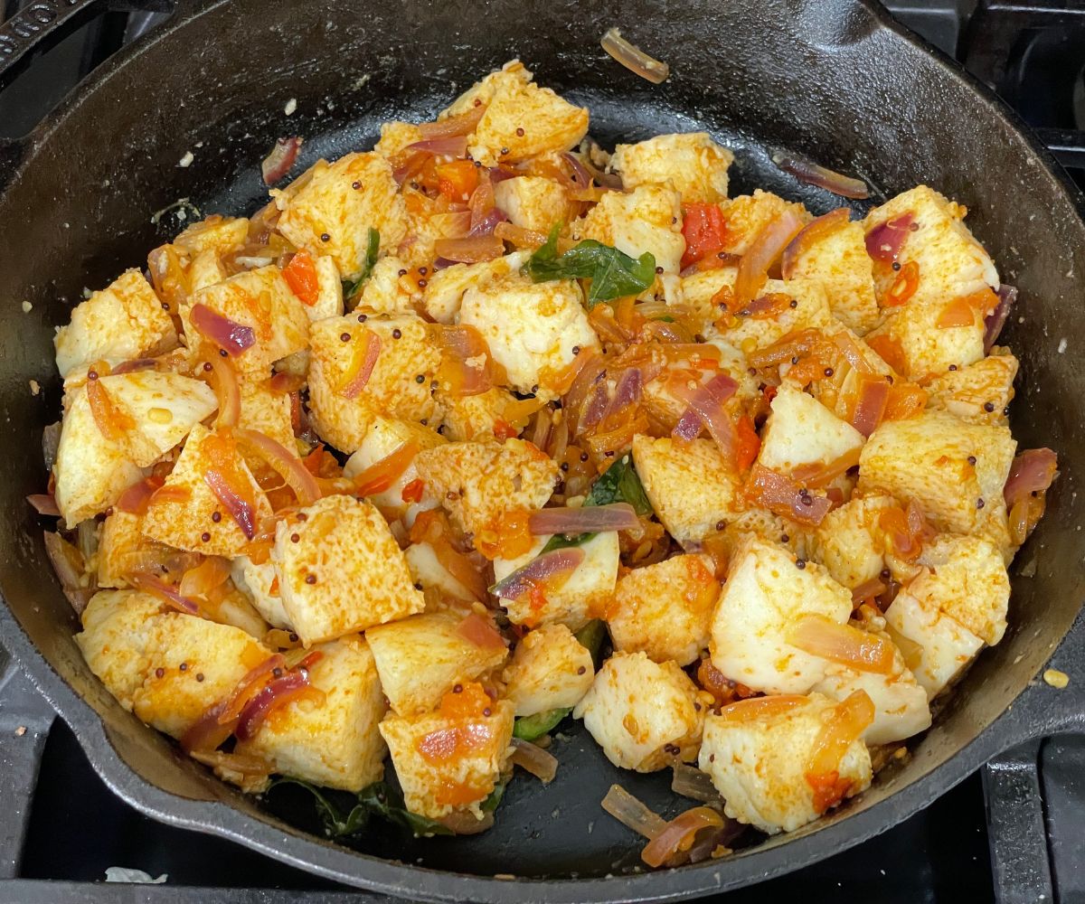A cast iron pan is with masala idlis over the heat.