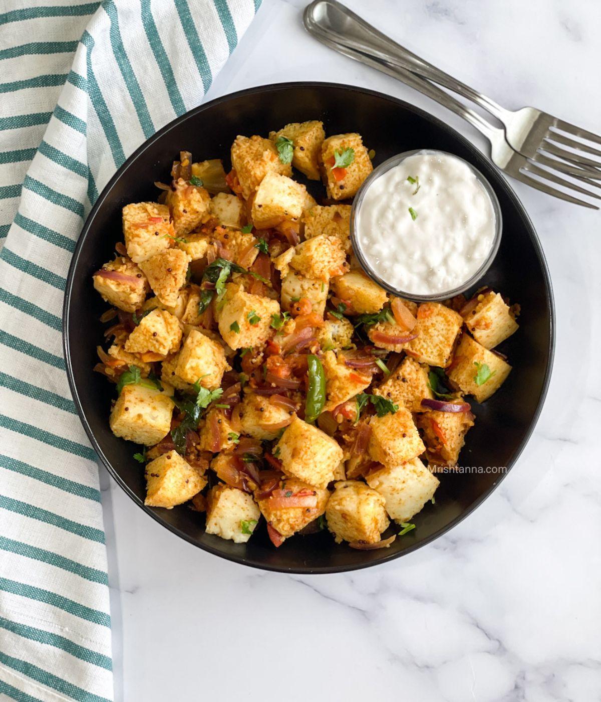 Head shot of masala idli with curd over the table.