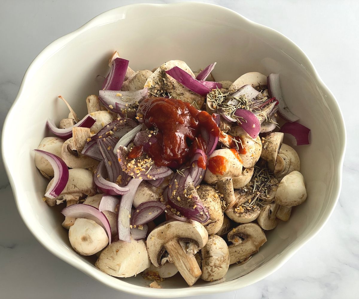 A bowl is with mushrooms, onions, spices on the table.