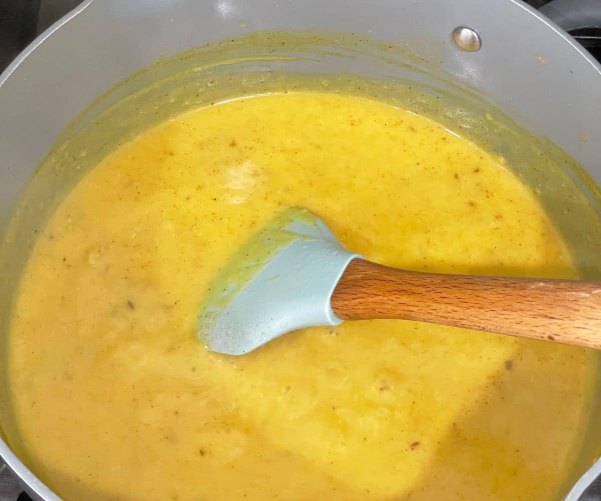 A pan is with cooked kadhi gravy over the heat.