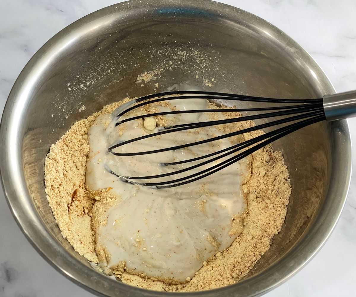 A bowl is with besan flour, yogurt and spices for kadhi batter.