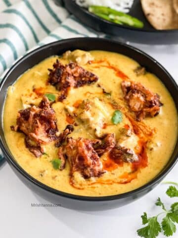 Close up of bowl filled with kadhi pakora curry.