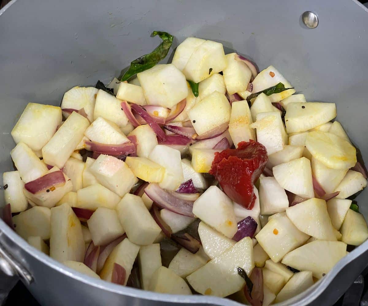 pot is with spices and chopped radish over the heat.